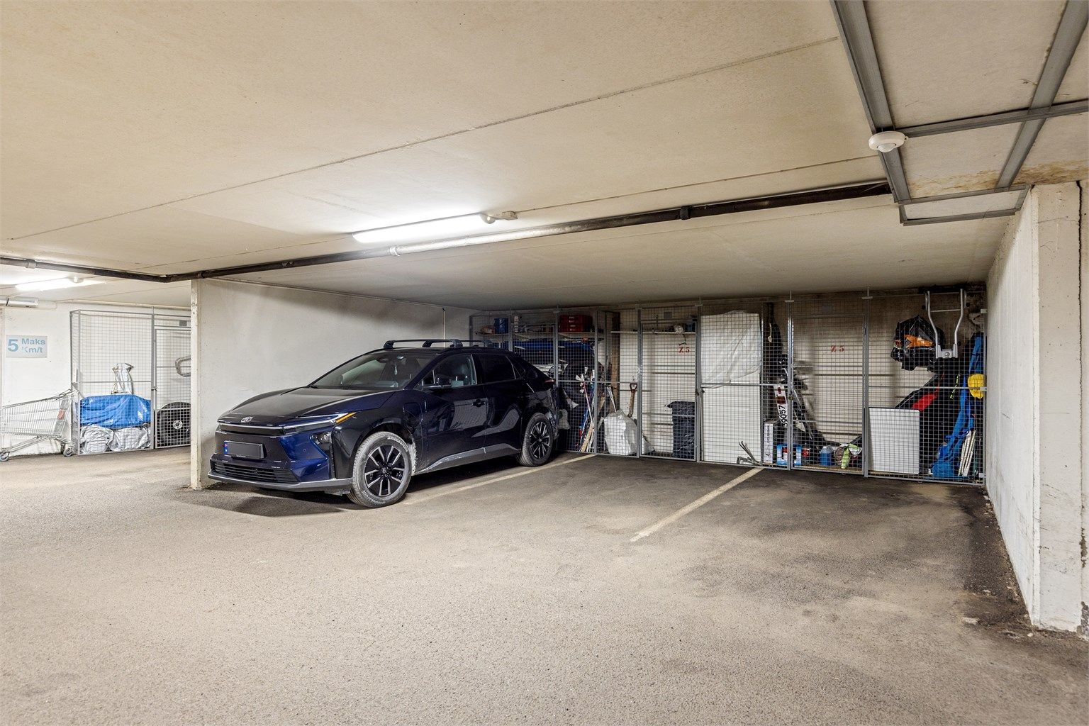 Leiligheten har garasjeplass i felles anlegg under blokken, med heisadkomst fra garasjeplan til leilighetsplan. ( Parkeringsplass til høyre i bildet)