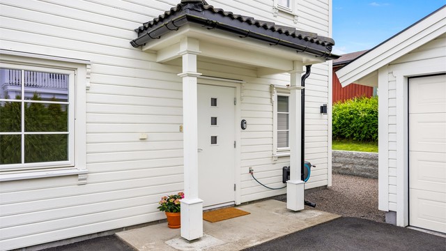 Overbygget inngangsparti og fasade med liggende trekledning.