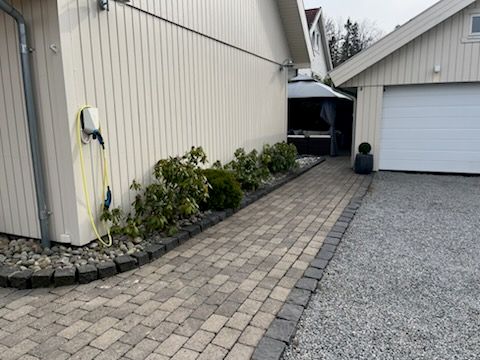Pent opparbeidet uteareal, med Herregaardsten, gruset innkjørsel, bedd og beplantinger.  