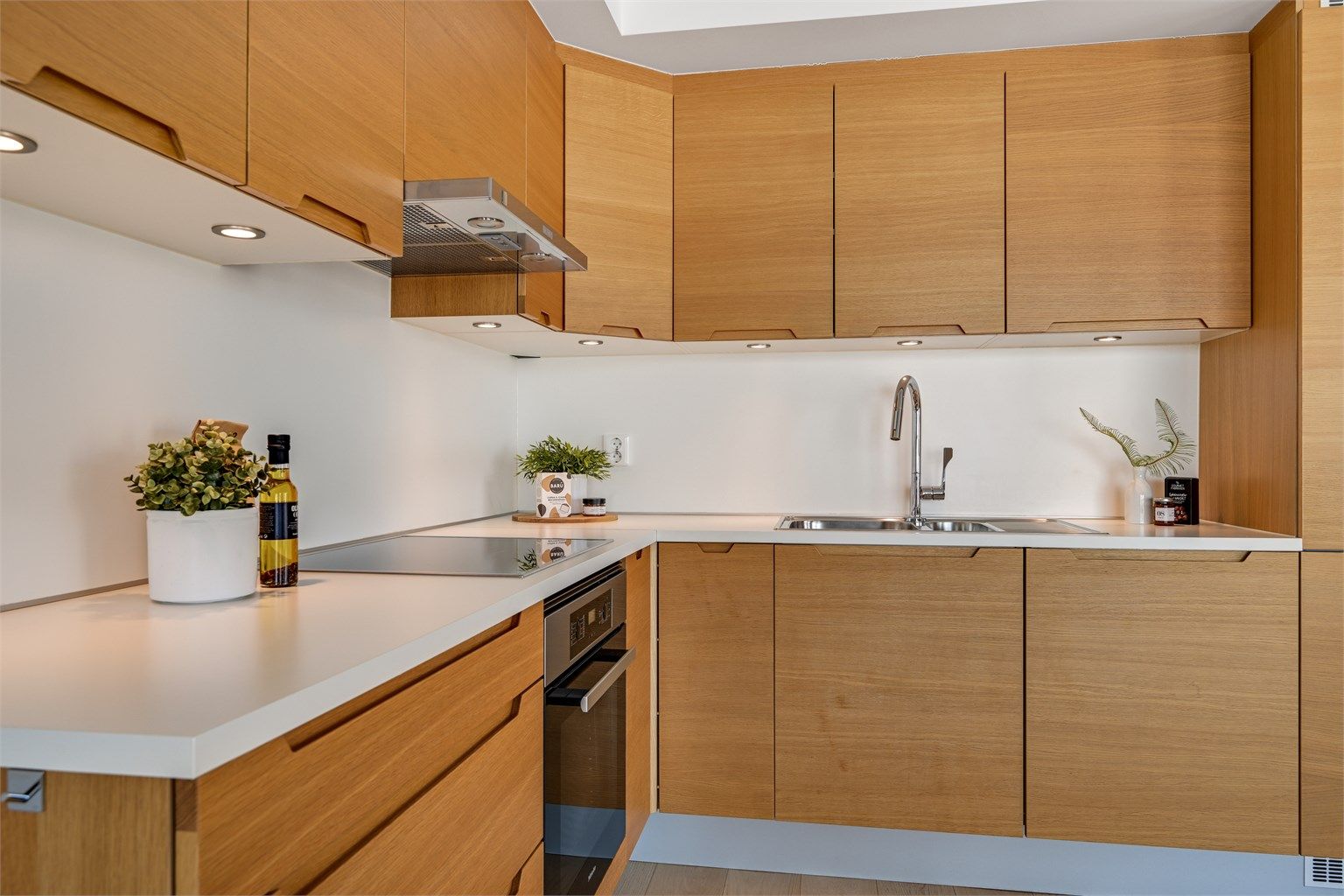 Kjøkkenet ligger i en åpen løsning mot stuen og er utført i moderne stil med lys under overskapene. 