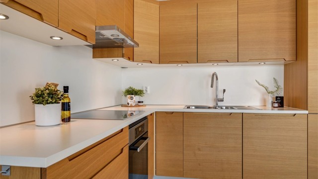 Kjøkkenet ligger i en åpen løsning mot stuen og er utført i moderne stil med lys under overskapene.