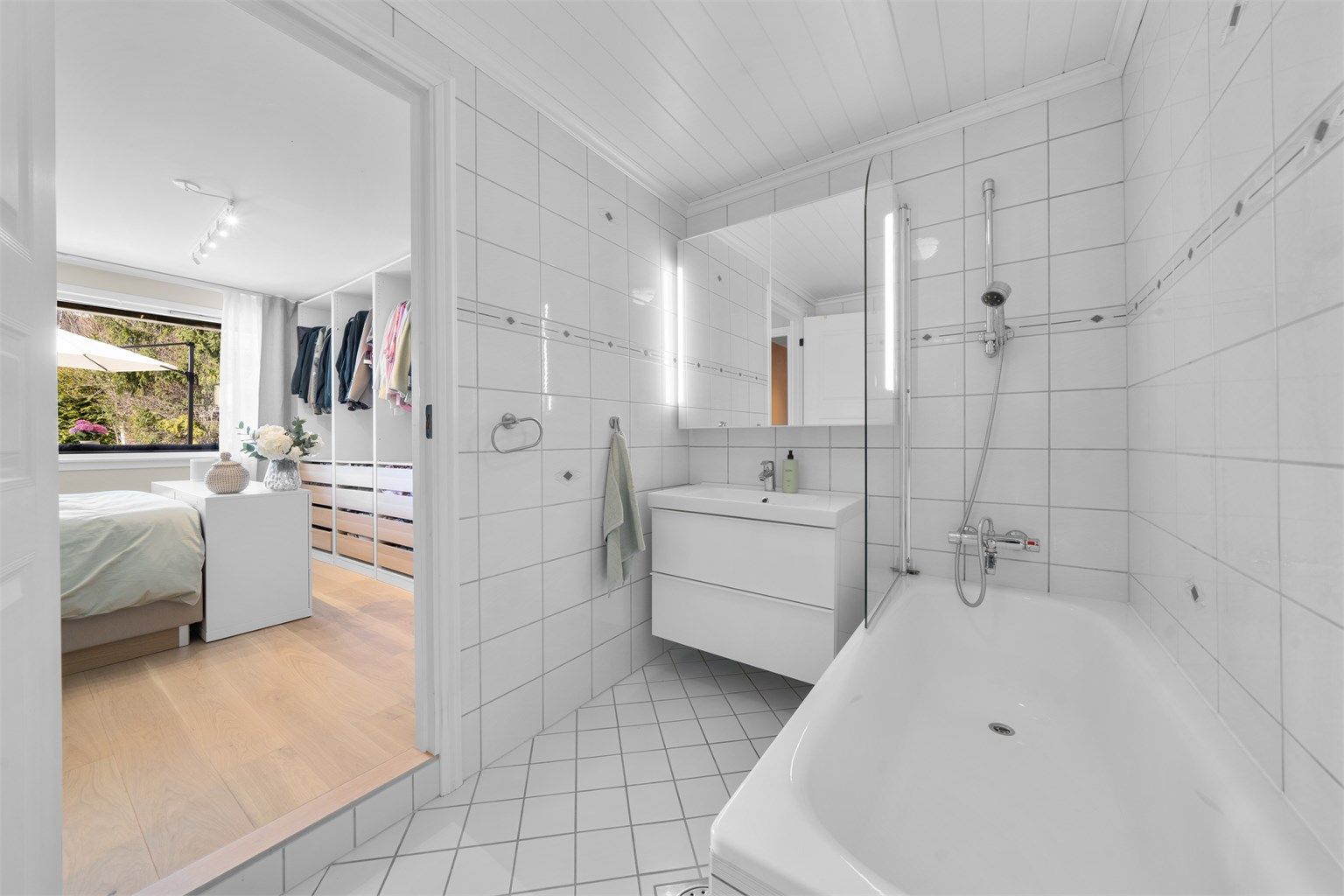 En suite bad med badekar, vegghengt servant og toalett