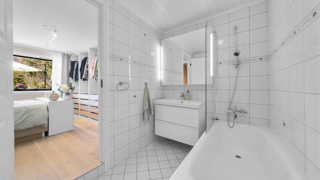 En suite bad med badekar, vegghengt servant og toalett