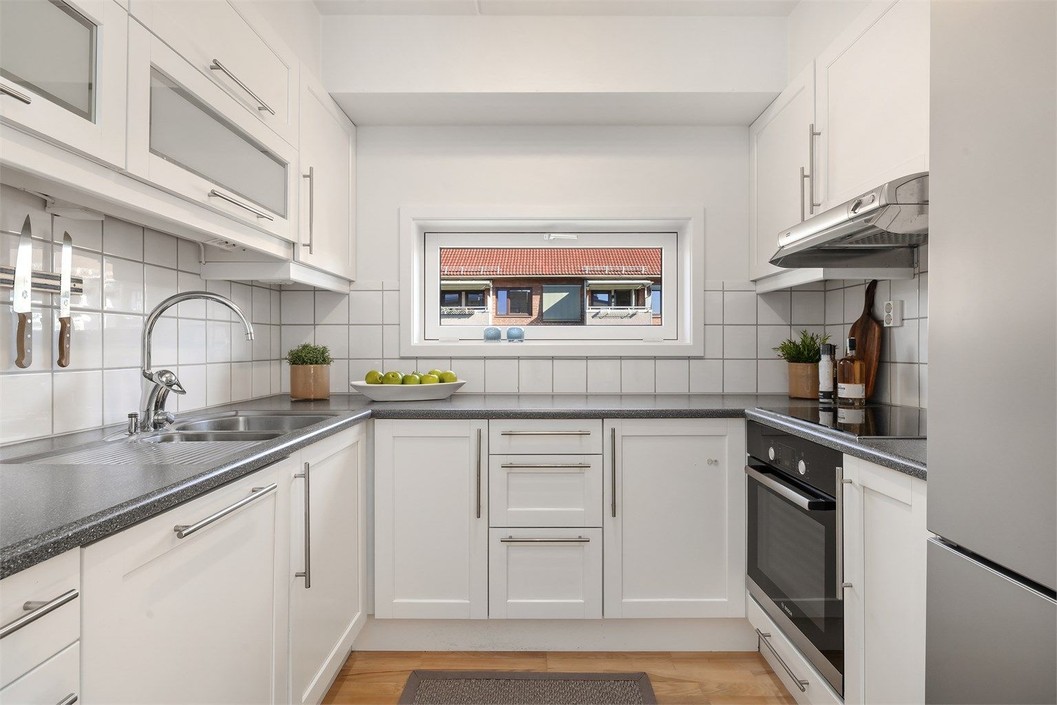 Kjøkkeninnredning med glatte fronter og laminat benkeplate med nedfelt vask og skyllekum. Siden dette er en endeleilighet så har rommet vindu på kjøkkenet