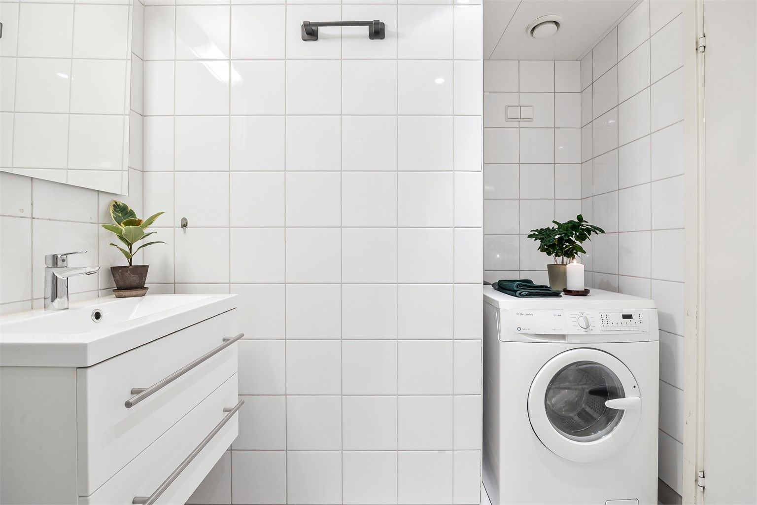 Videre er det dusjhjørne med dører, vegghengt toalett og opplegg for vaskemaskin.
