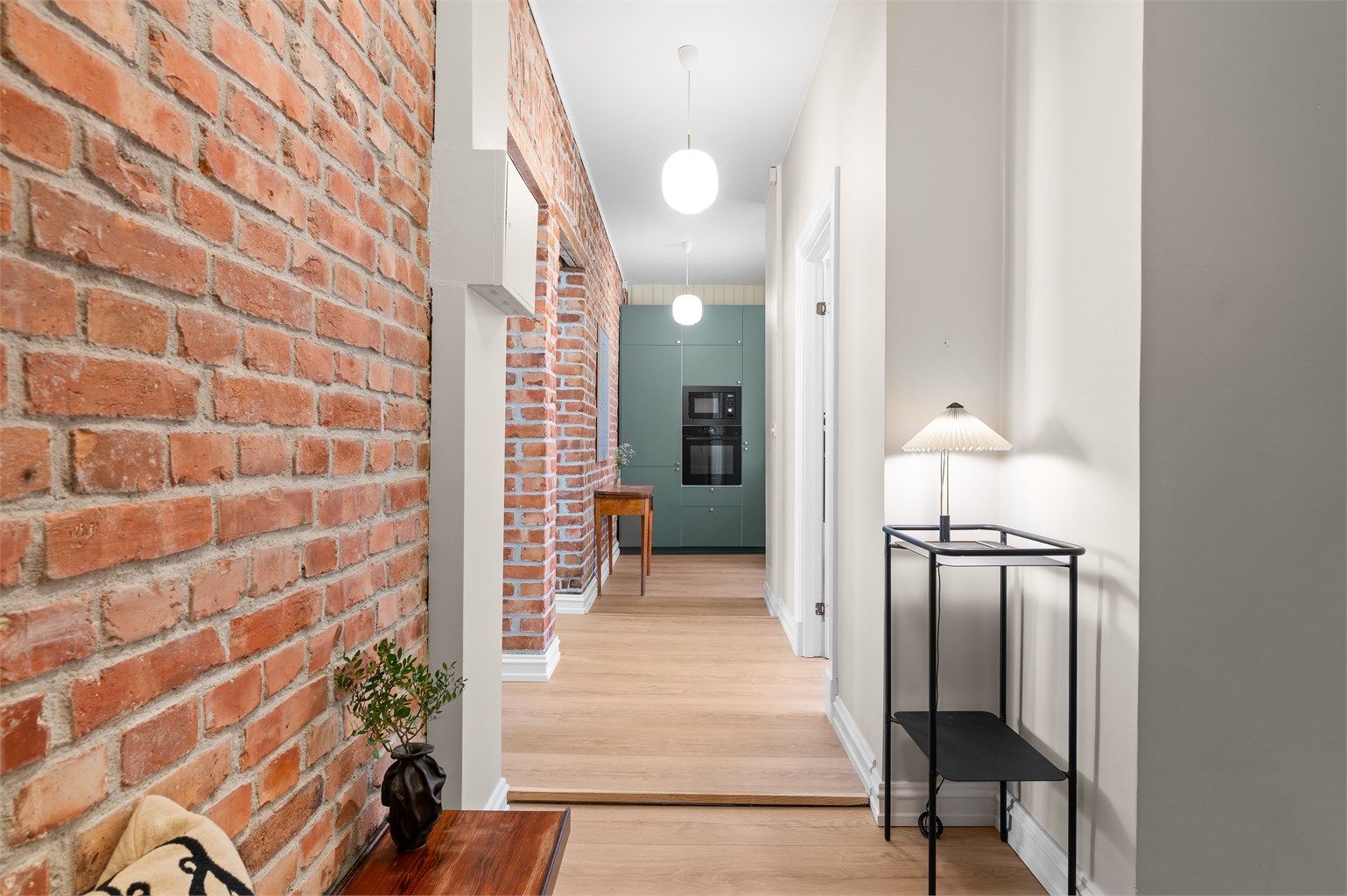 Den lange siktlinjen gjennom gangen mot kjøkkenet understreker den åpne planløsningen.