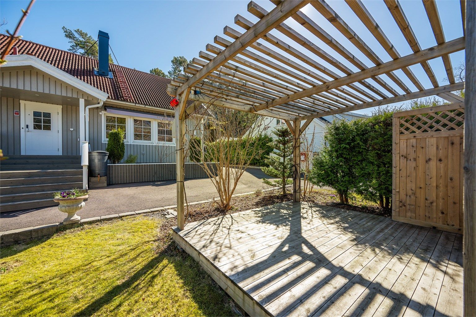 En pergola i hagen skaper en lun og definert uteplass.