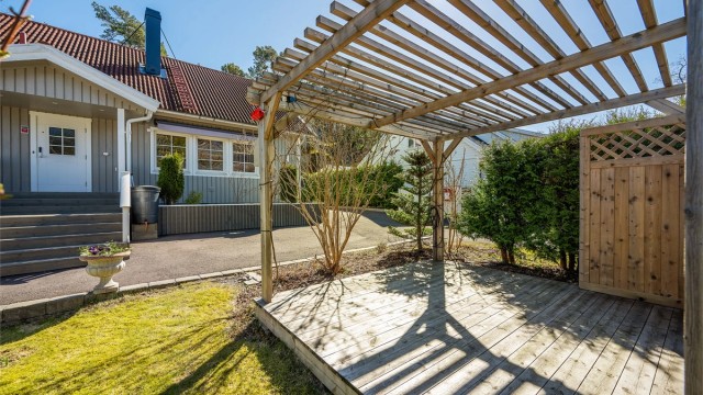 En pergola i hagen skaper en lun og definert uteplass.
