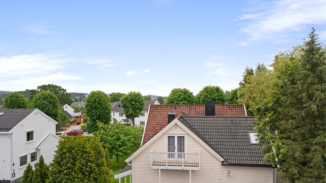 Utsikt over hustakene ned igjennom og mot sjøen i horisonten
