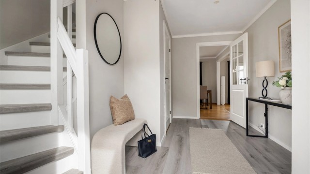 Lys og innbydende hall med nytt laminatgulv fra 2024. Trappen har laminat i trinnene og malt rekkverk.