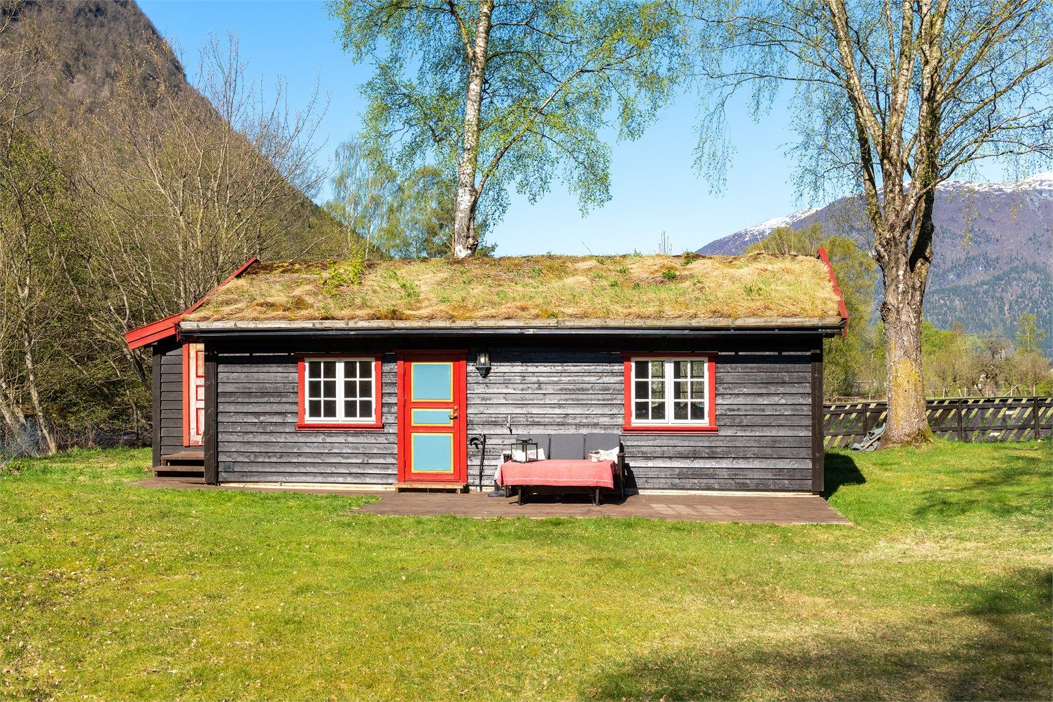 En praktisk og moderne hytte som komplementerer de eldre bygningene på tunet.