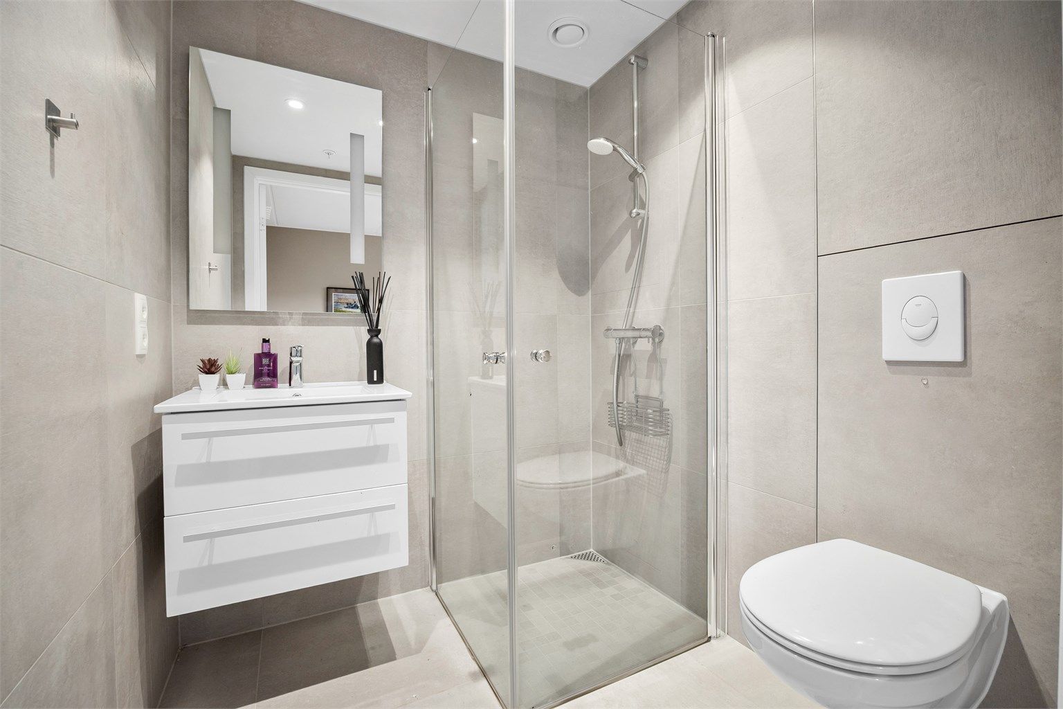 Stilrent bad 2 med store flisoverflater, tilknyttet hovedsoverommet. Badet har dusjhjørne, downlights i tak og varmekabler.
