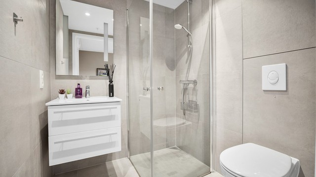 Stilrent bad 2 med store flisoverflater, tilknyttet hovedsoverommet. Badet har dusjhjørne, downlights i tak og varmekabler.