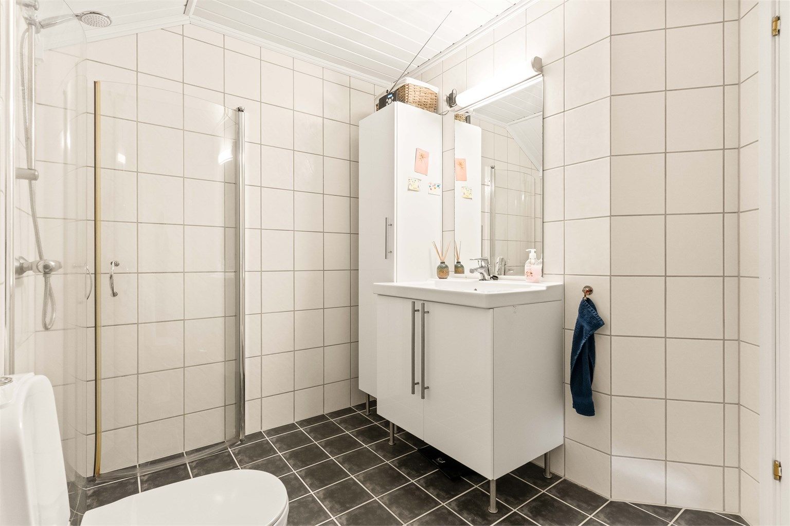 Badet er utstyrt med servantinnredning, dusjhjørne og mekanisk avtrekksvifte.