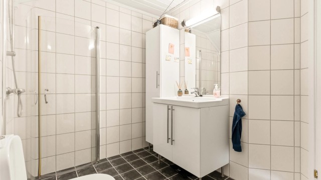 Badet er utstyrt med servantinnredning, dusjhjørne og mekanisk avtrekksvifte.