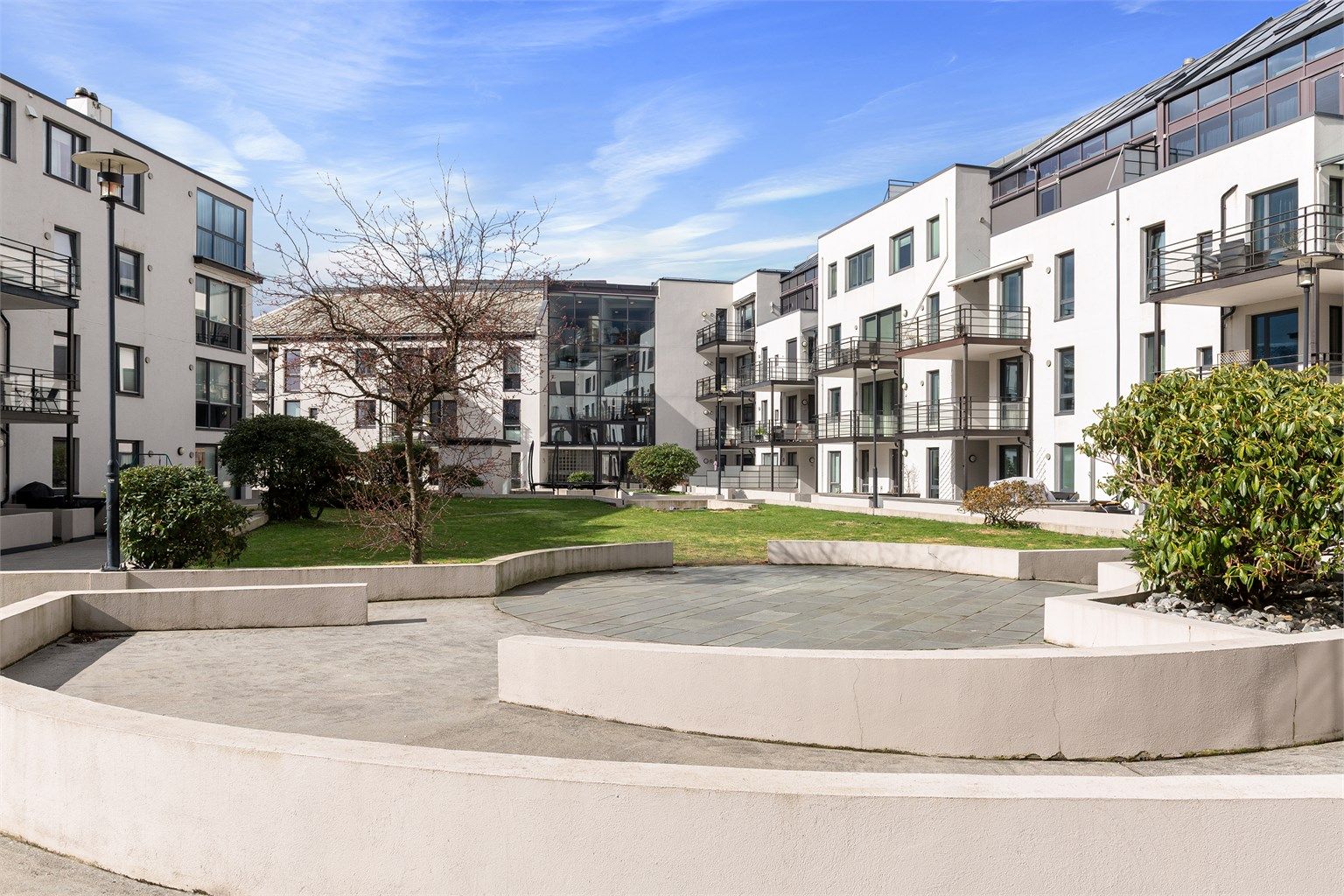 Sameiet har et pent opparbeidet og skjermet fellesareal med plen og sitteplasser