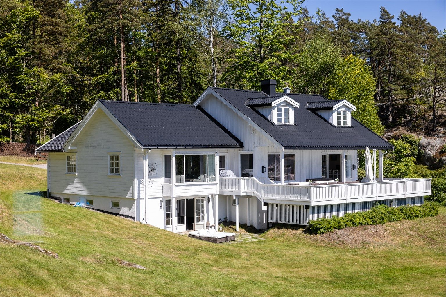 Hovedhuset sett fra siden, med store vindusflater mot sjøen.