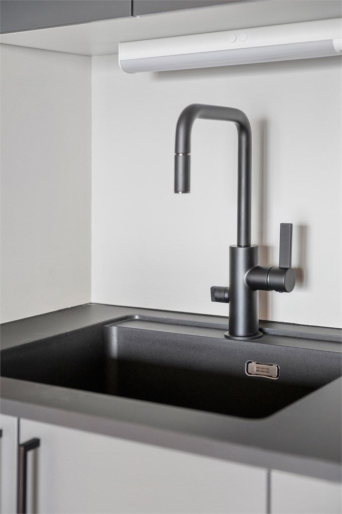 Kjøkkenet er utstyrt med innredning med mørke glatte fronter, benkeplate i laminat med nedfelt oppvaskkum med blandebatteri.