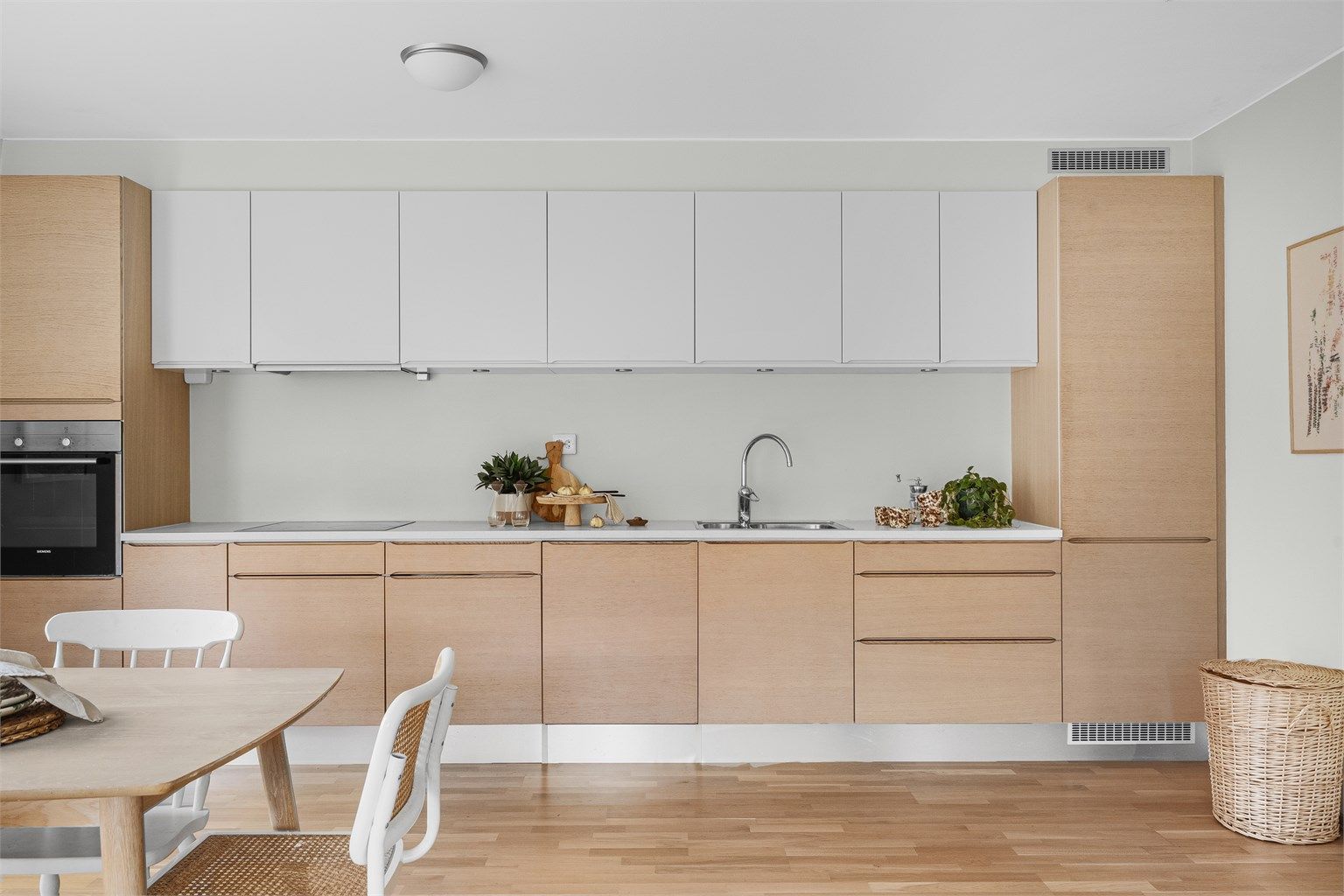 Kjøkkenet er i moderne og fint design med fronter i eik og hvitt. Lys benkeplate. Kjøkkeninnredning er fra HTH og det er integrerte hvitevarer, spotter under overskap og godt med benke - og skapplass.