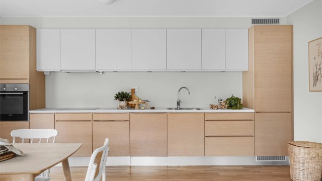 Kjøkkenet er i moderne og fint design med fronter i eik og hvitt. Lys benkeplate. Kjøkkeninnredning er fra HTH og det er integrerte hvitevarer, spotter under overskap og godt med benke - og skapplass.