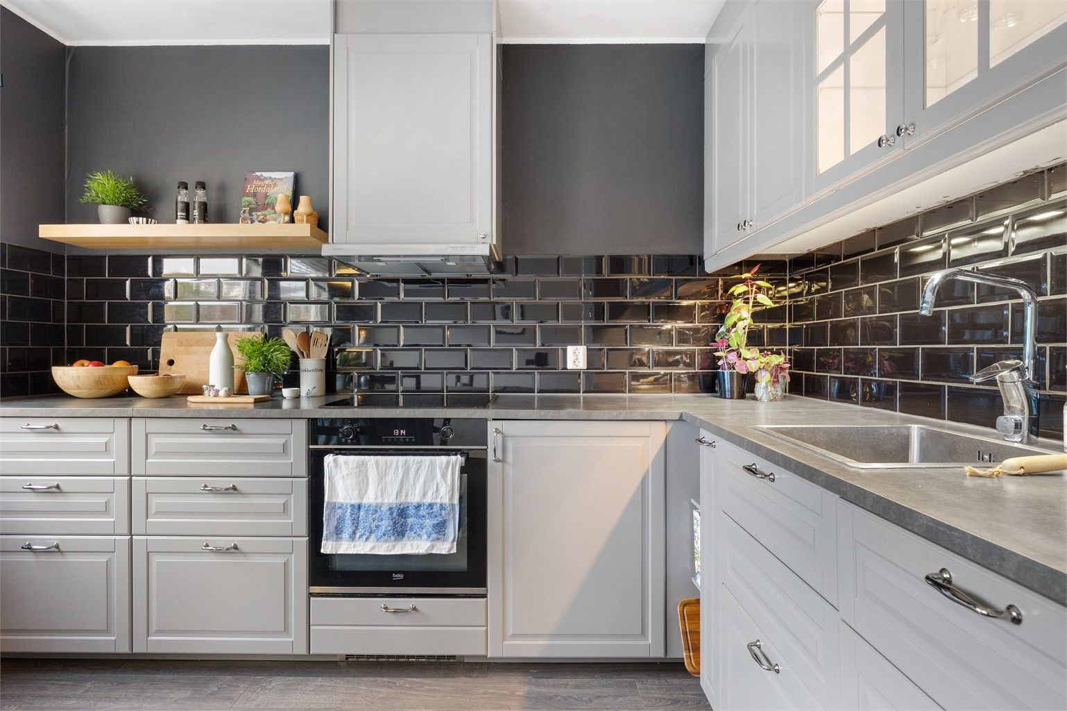 Moderne kjøkken med integrerte hvitevarer som platetopp, stekeovn og oppvaskmaskin, med et tidløst materialvalg