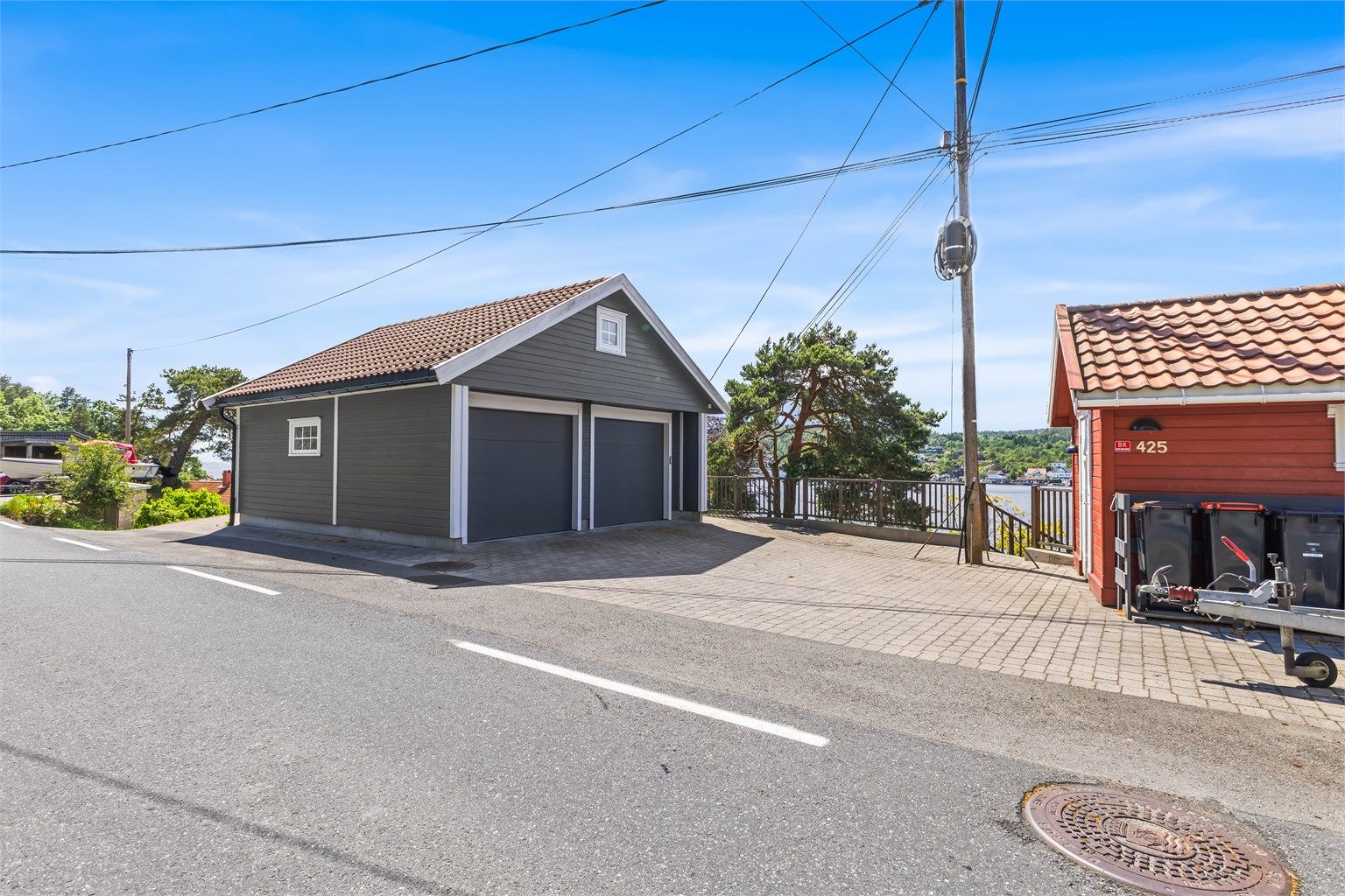 Nyere, romslig dobbelgarasje fra 2015 med innlagt strøm og elbillader. Det er også en praktisk redskapsbod som tilhører (rød) og god plass til flere biler på brostein.
