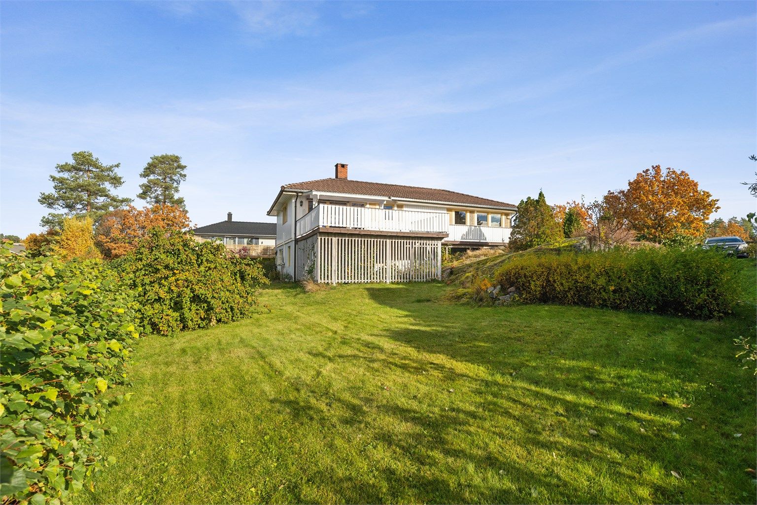 Tomten har en romslig plen med vakker beplanting, prydbusker og trær som gir både farge og skjerming gjennom sesongen. 