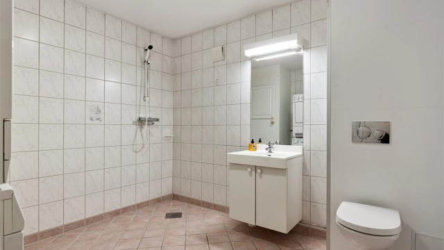Romslig flislagt baderom i kjeller gir ekstra komfort til barnefamilier i hverdagen. Rommet har vegghengt toalett, dusjhjørne, servant med underskap samt opplegg til vaskemaskin og plass til tørketrommel