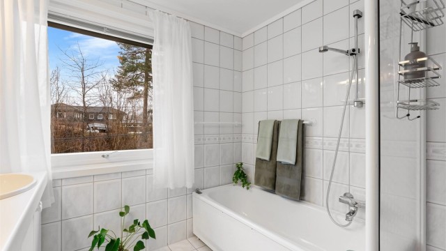 Rommet er utstyrt med både badekar og et separat dusjhjørne med skyvedør.