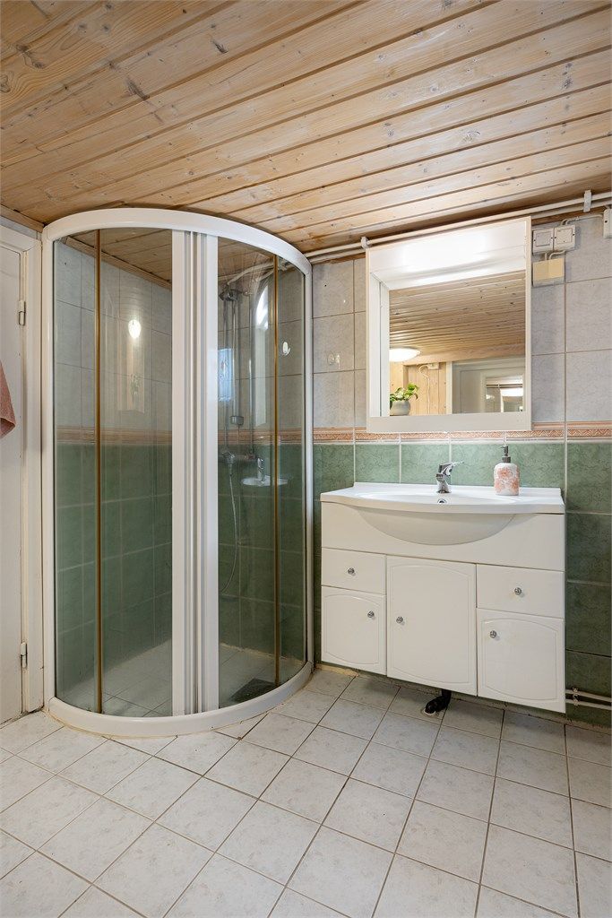 Badet er utstyrt med dusjhjørne med dører, servantinnredning og toalett.