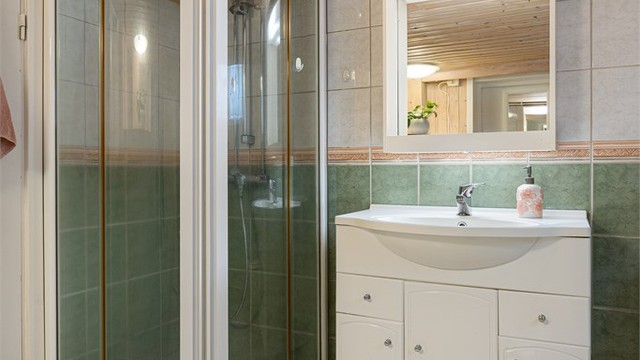 Badet er utstyrt med dusjhjørne med dører, servantinnredning og toalett.