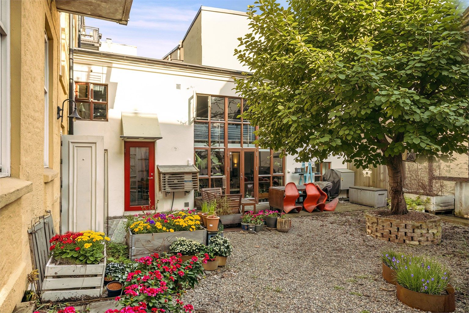 Hyggelig bakgård med plass til sittegrupper. Blomster er Ai generert. 