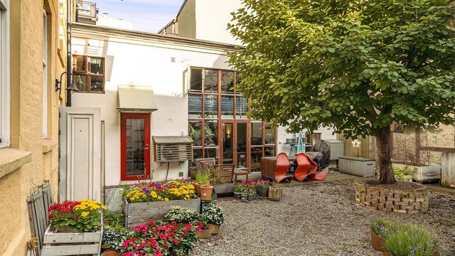 Hyggelig bakgård med plass til sittegrupper. Blomster er Ai generert.