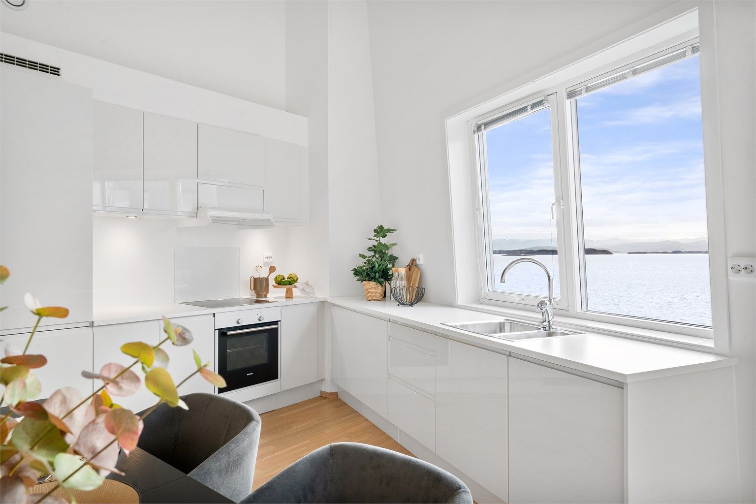 Kjøkkenet er i moderne og fint design fra HTH med lyse fronter og lys benkeplate. Ved kjøkkenet er det god plass til spisebord og det er flott sjøutsikt.