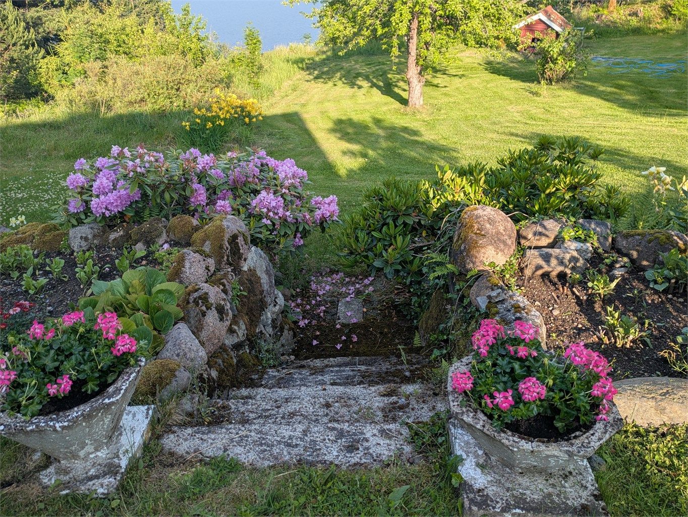 Eiendommen er velholdt med langvarig og gjennomført opparbeidelse, der beplantning, steinbed, trapper og gressarealer skaper et vakkert og strukturert hagemiljø (selgers bilde)