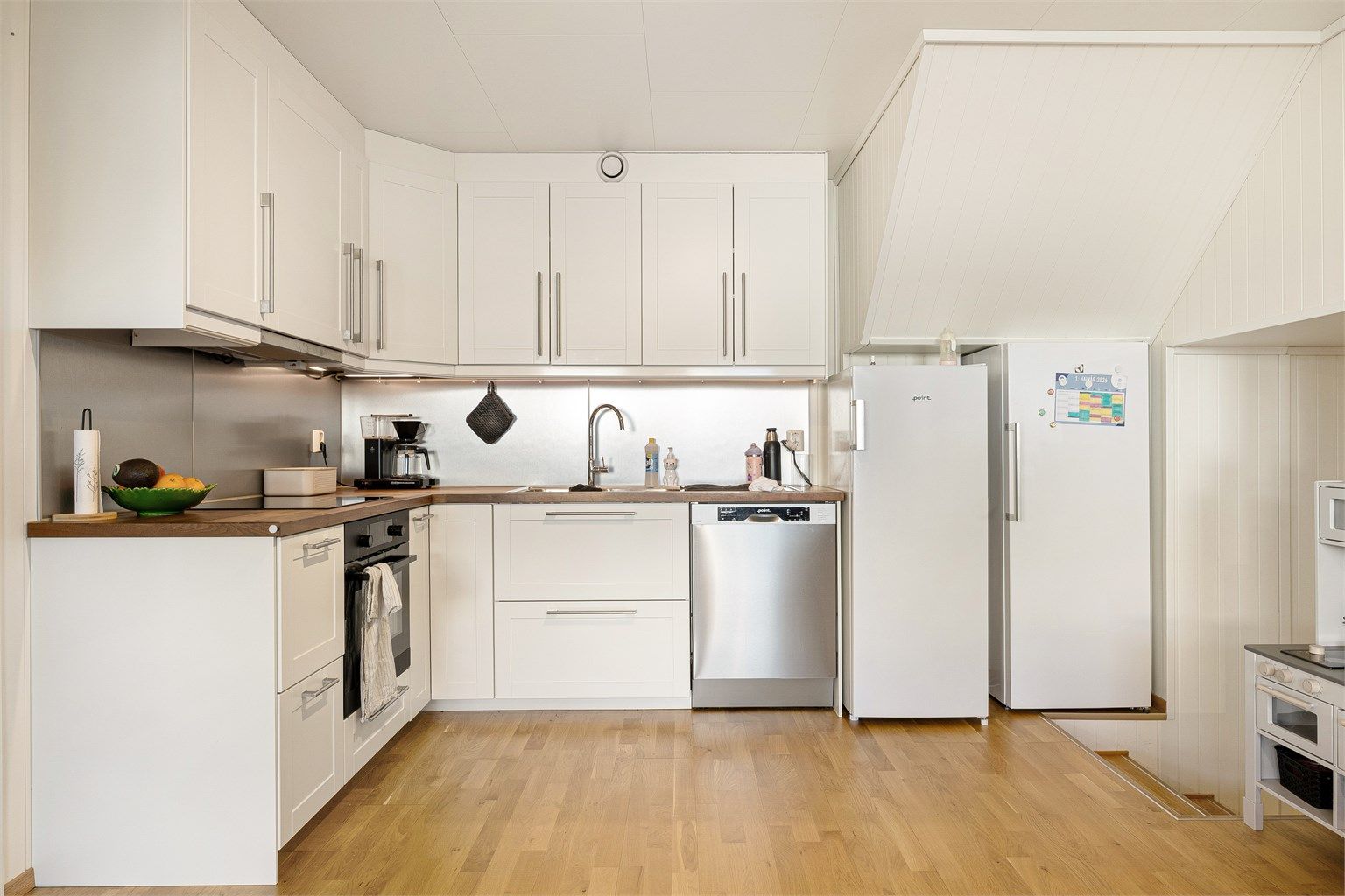 Kjøkkeninnredninger er fra 2014 med profilerte fronter og benkeplate i tre. Mellom kjøkkenbenk og overskap er det montert laminerte plater. Integrert stekeovn og platetopp og frittstående oppvaskmaskin og kjøleskap.