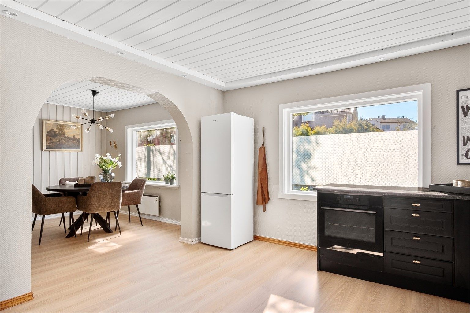 Nytt laminatgulv lagt gjennomgående mellom spisestuen og kjøkkenet skaper visuell helhet.