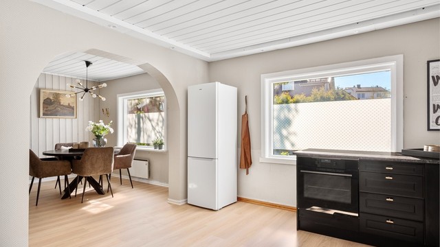 Nytt laminatgulv lagt gjennomgående mellom spisestuen og kjøkkenet skaper visuell helhet.