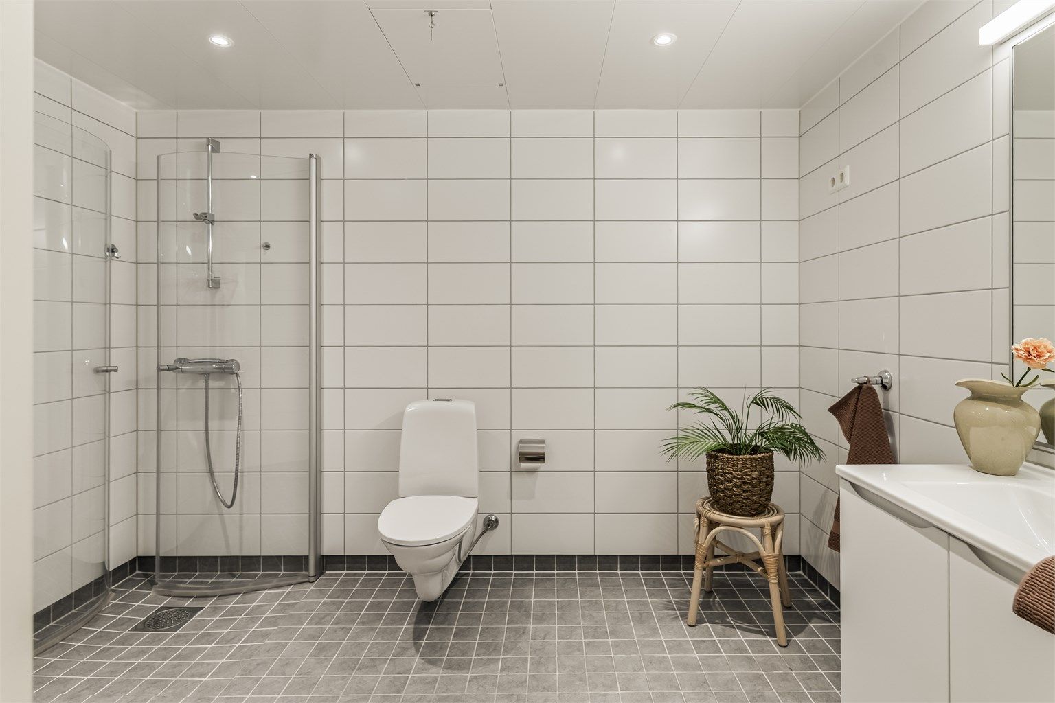 Hovedbadet er helfliset og har gulvvarme, vegghengt toalett og et romslig dusjhjørne med glassvegger.