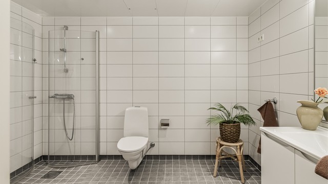 Hovedbadet er helfliset og har gulvvarme, vegghengt toalett og et romslig dusjhjørne med glassvegger.