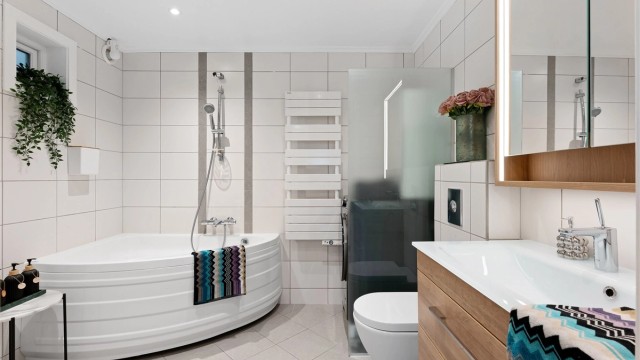 Pent baderom med fliser på gulv med gulvvarme, fliser på vegger og malt himling