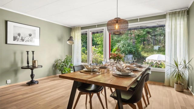 Spisestuen har store vinduer med utsikt mot hagen og skogen.