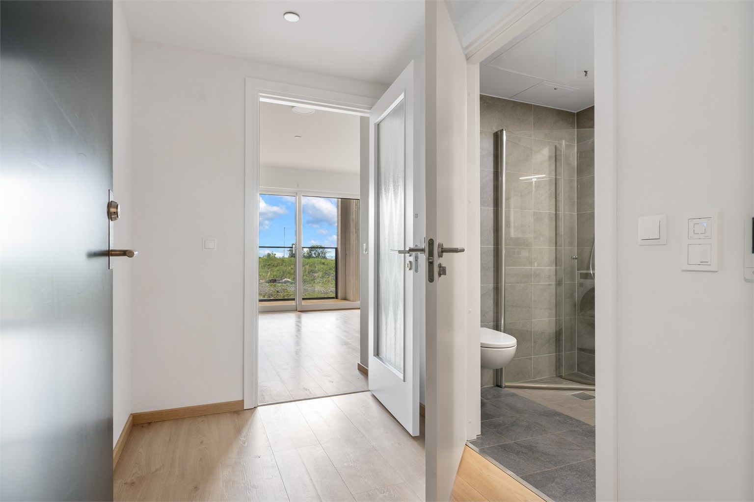 Entréen har adkomst til badet og leder videre inn til stuen. Vannbåren gulvvarme gir en lun velkomst.
