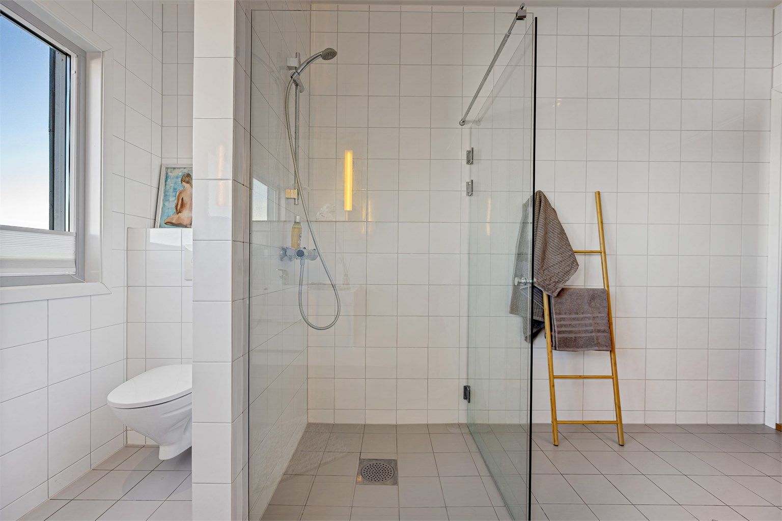 Rommet er utstyrt med dusjnisje med glassvegg og vegghengt toalett.