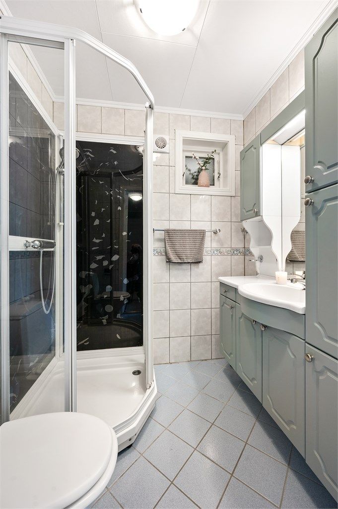 Badet i første etasje har flislagt gulv med gulvvarme, flislagte vegger og dusjkabinett.