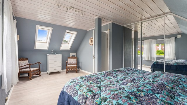 En stor skyvedørsgarderobe med speilfronter gir rikelig med oppbevaringsplass på hovedsoverommet.