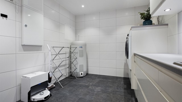 Romslig vaskerom med stor innredning med god plass til vaskemaskin og tørketrommel