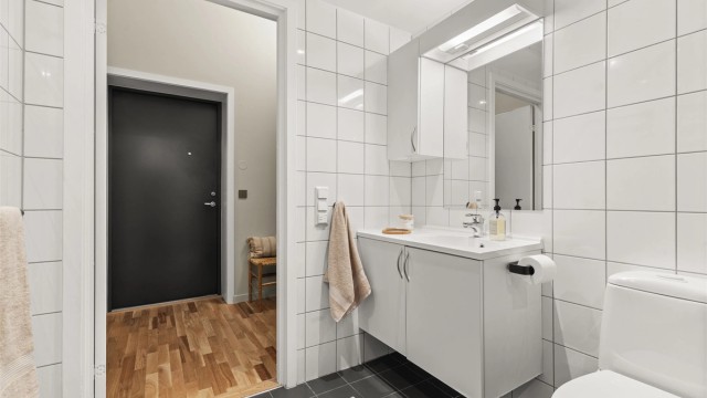 Badet har vegghengt toalett, god oppbevaringsplass og funksjonelle løsninger.