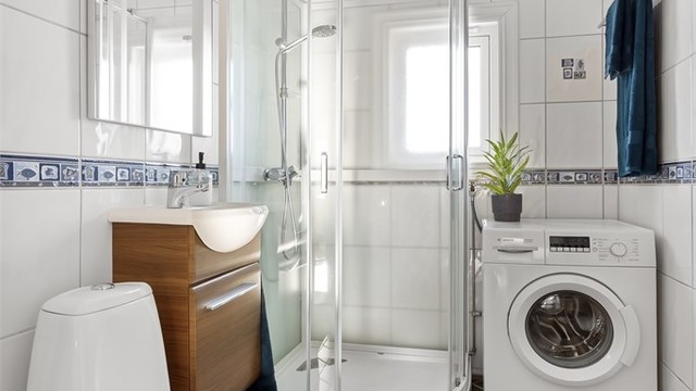 Badet er innredet med servant, speil, høyskap og toalett.