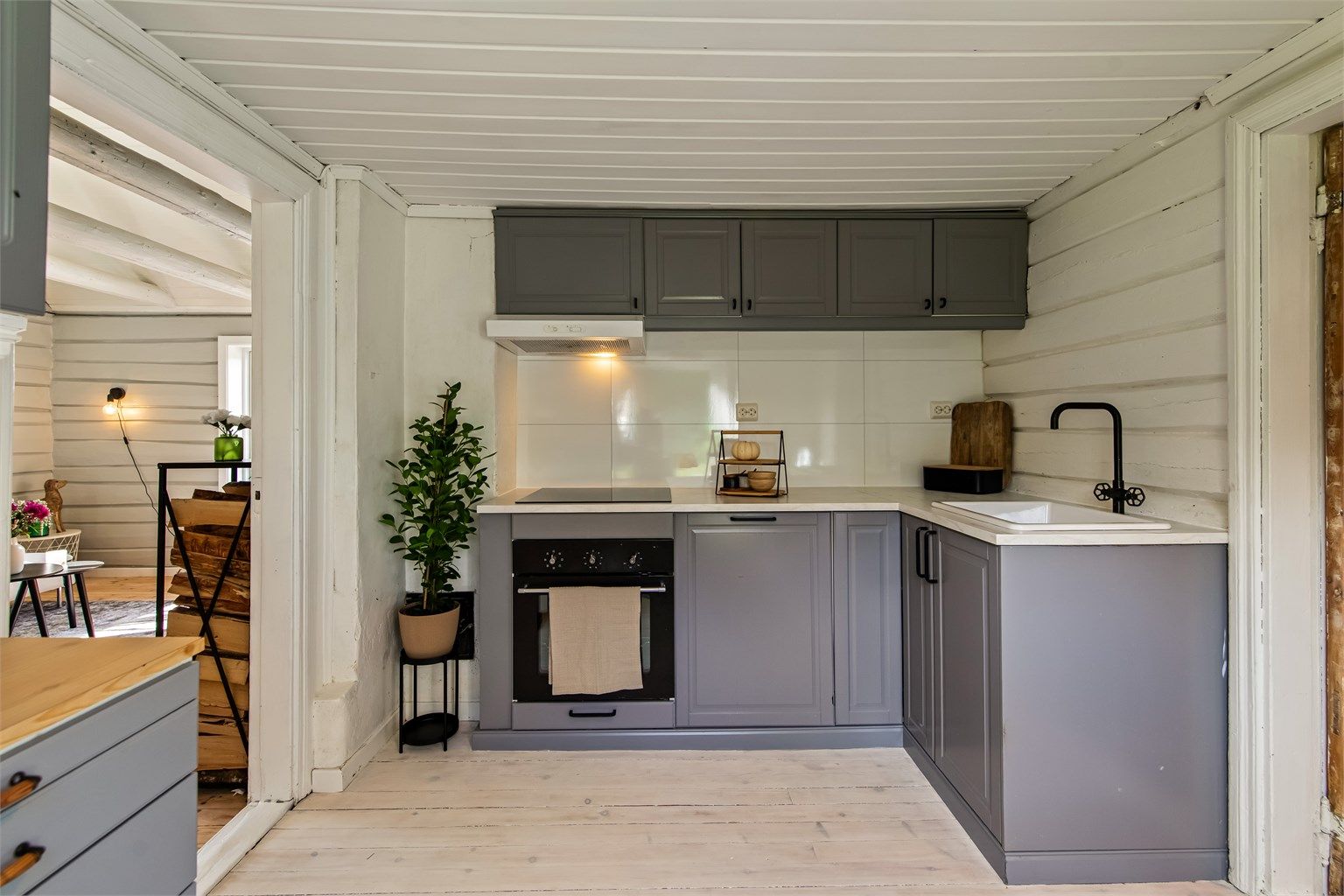 Kjøkkeninnredning med profilerte fronter, laminert benkeplate og oppvaskkum i porselen. Det er montert platetopp og komfyr samt opplegg til oppvaskmaskin.